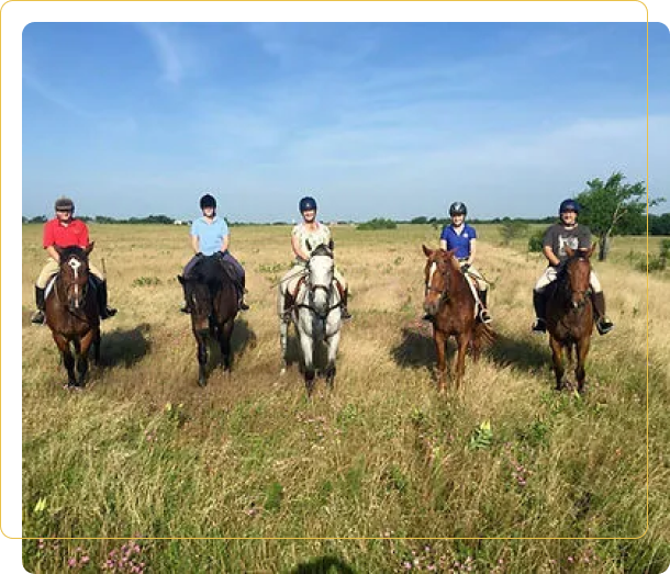 A group of people riding horses in the grass.