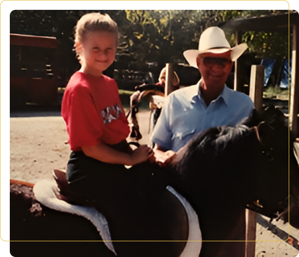 A man and child on horseback in an amusement park.