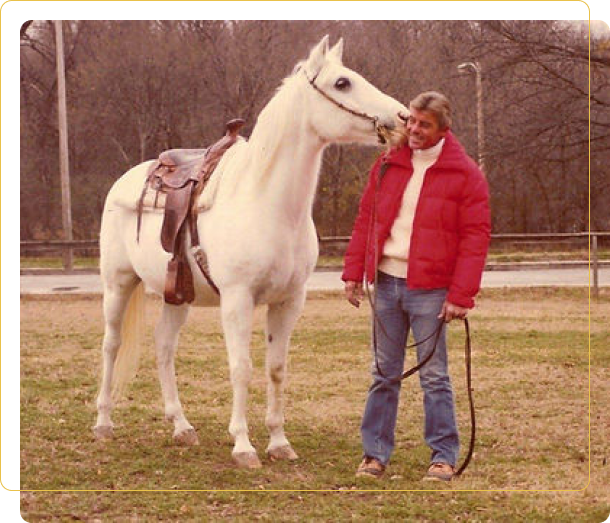 A man standing next to a white horse.