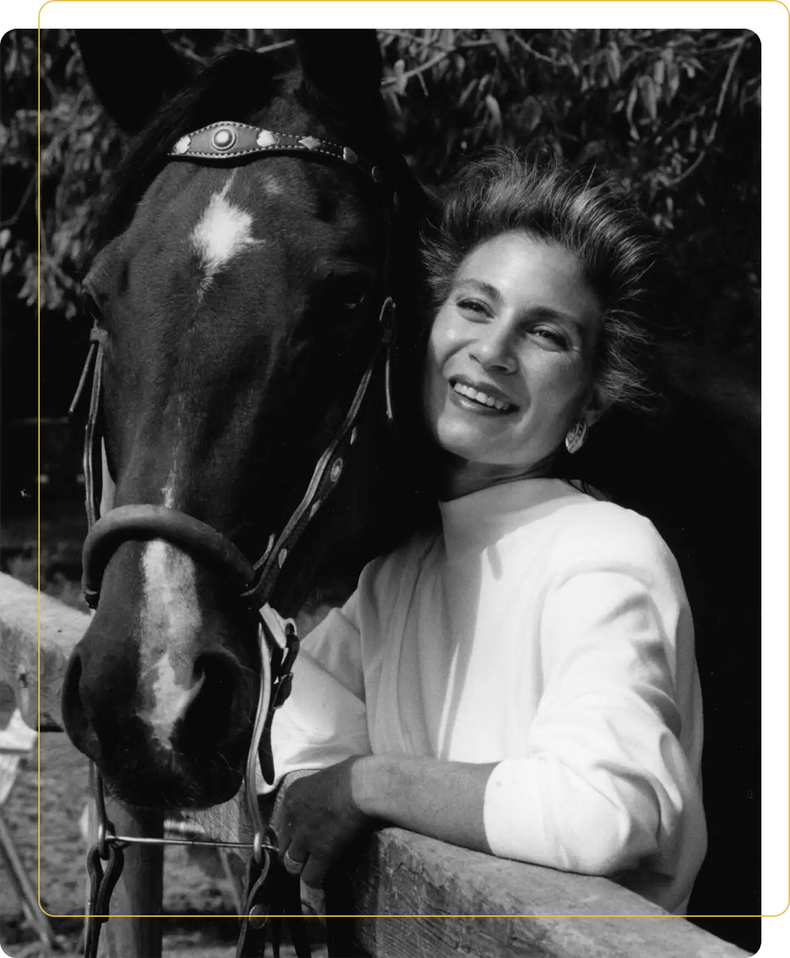 A woman standing next to a horse in front of trees.