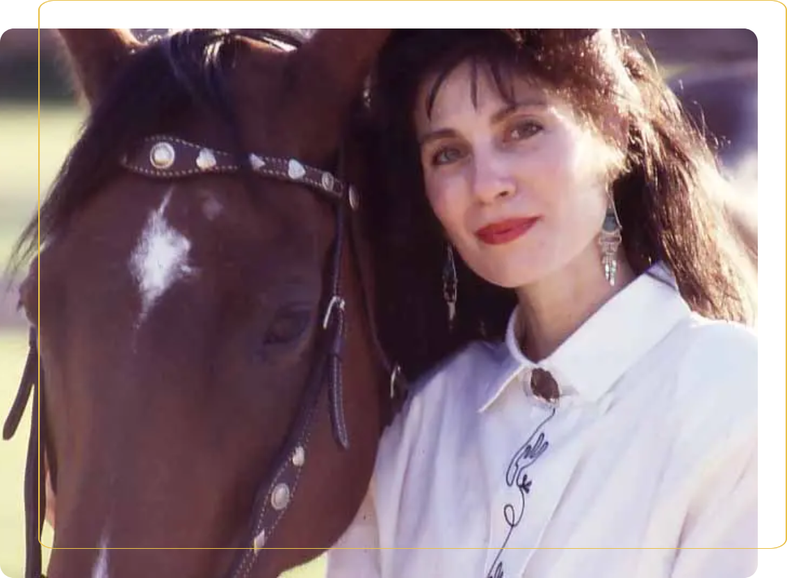 A woman standing next to a horse with her head on the back of it.